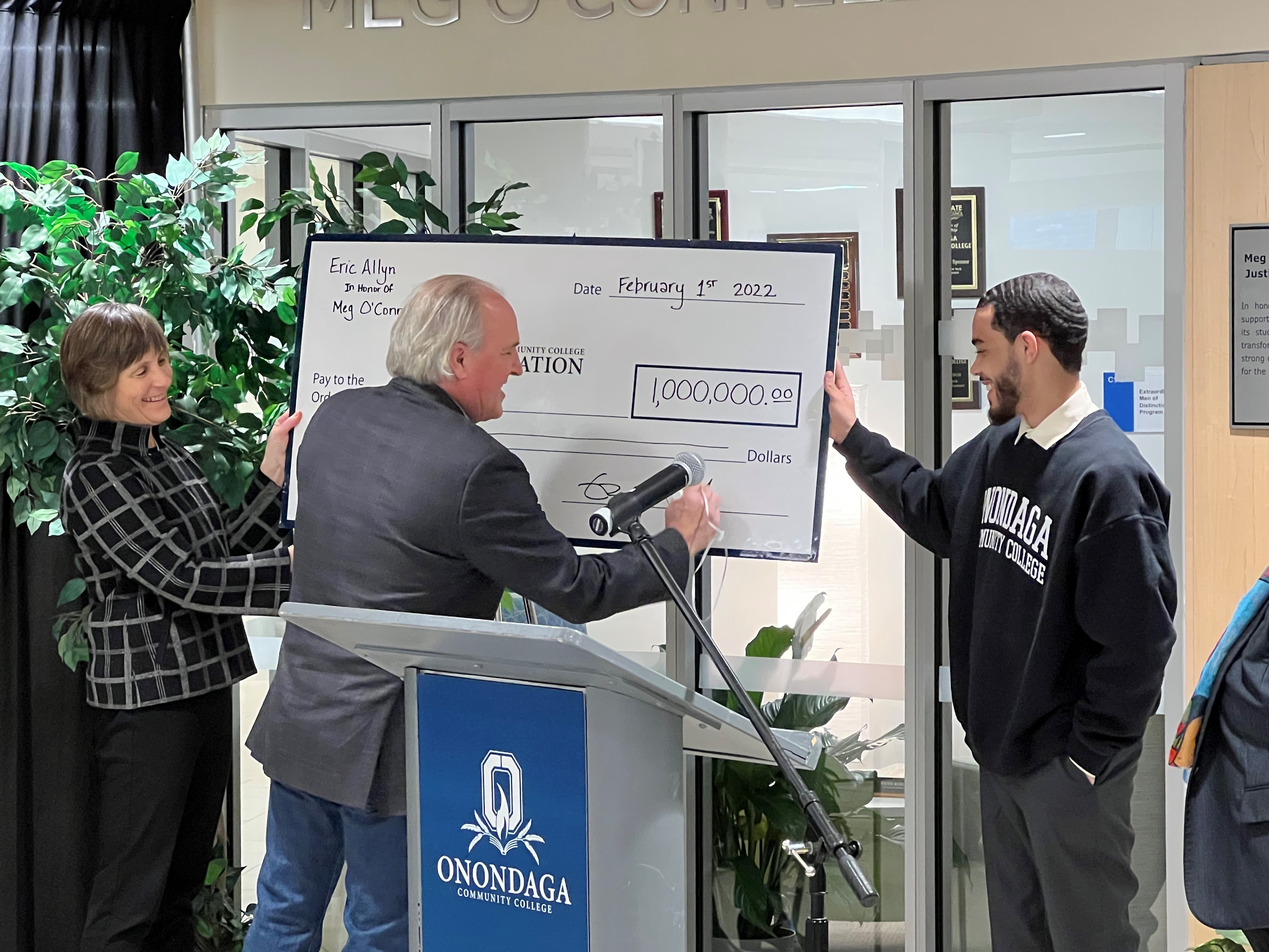 Eric Allyn (center) signs the ceremonial check. Joining him are his wife, Meg O'Connell (left) and OCC student Angel Gonzalez.