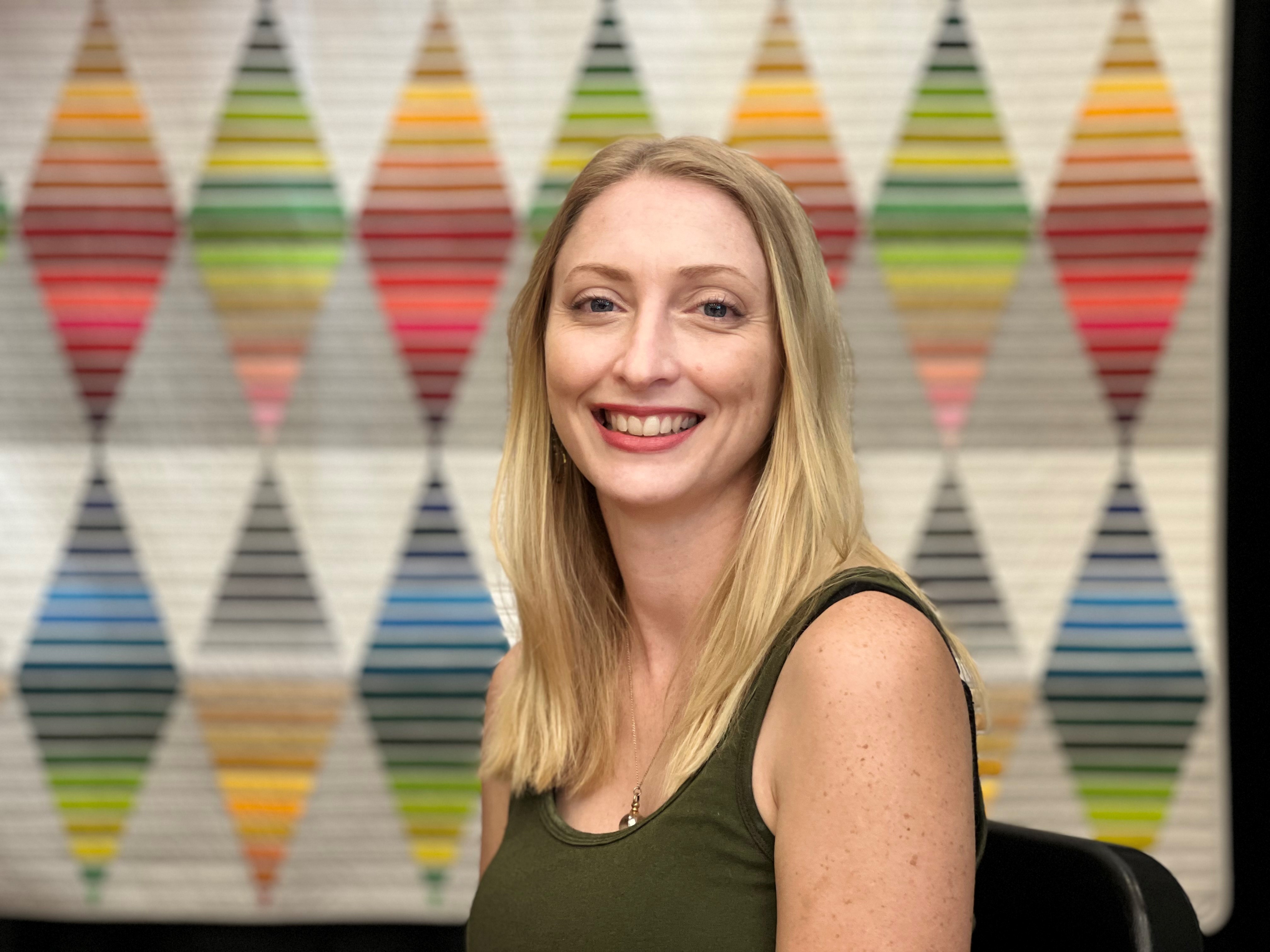 Davana Robedee is Program Director for QBL. She's pictured in front of a quilt titled "Diamond Color Story" by Sarah Bond of Philadelphia.