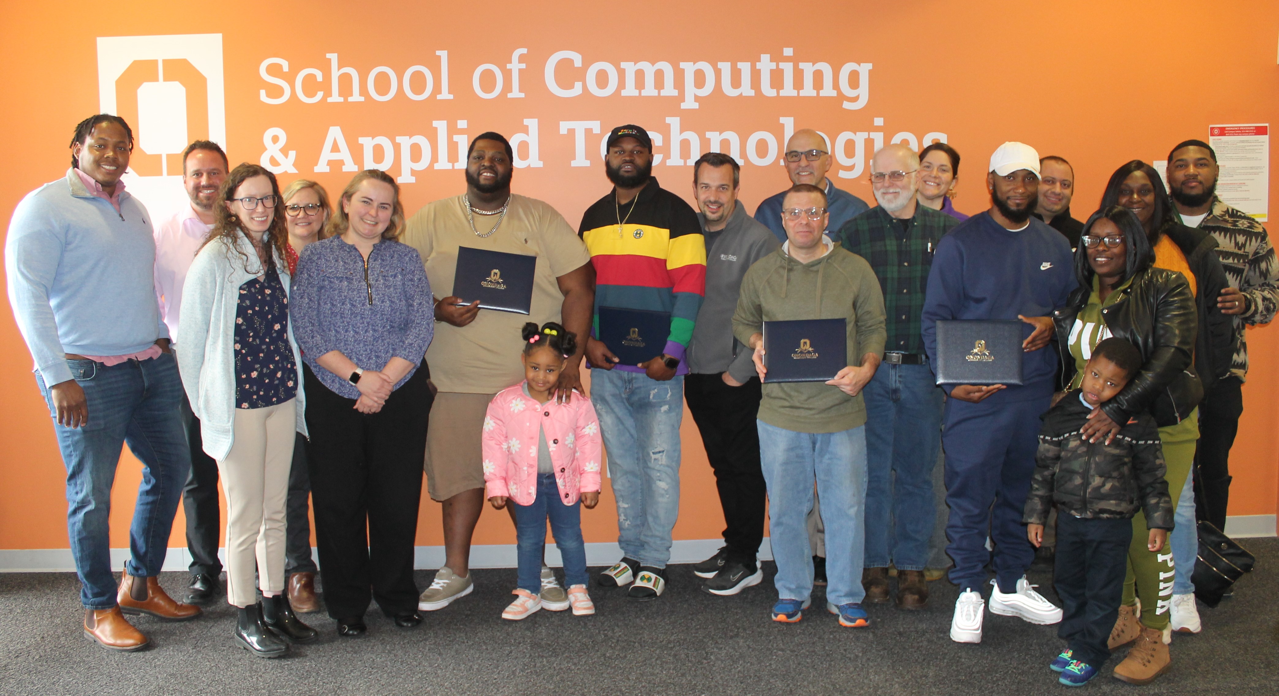 Program graduates, family members, and support staff pose for a group photo outside OCC's Electromechanical Lab.